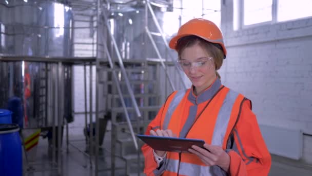 Forceful woman at factory, portrait of engineer female into hard hat and coveralls with computer tablet making calculated decisions — Stock Video