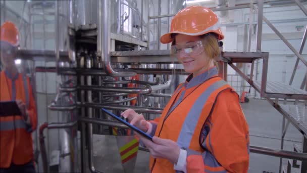 Retrato de la mujer trabajadora industrial feliz en el sombrero duro y en general con la tableta de computadora que toma decisiones de ingeniería calculadas — Vídeos de Stock