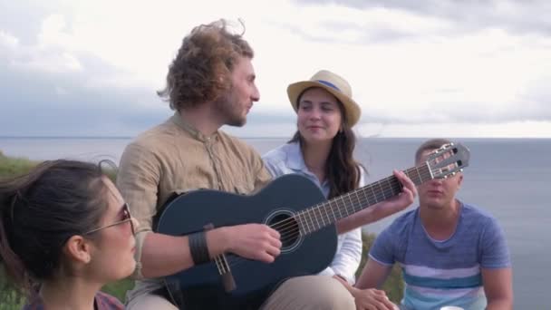 Flirtování, mladá veselá dívka v lásce flirtuje oči na chlapa hrající na kytaru během přátel párty v přírodě — Stock video