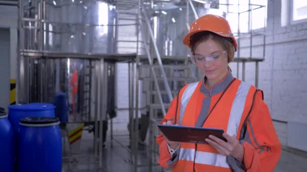 Сильна жінка на заводі, заводський працівник жінка в шолом і в цілому з цифровим планшетом приймає розрахункові інженерні рішення — стокове відео
