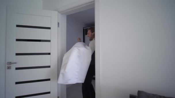 Happy bridegroom carries bride on hands in white dress and turns at new flat on wedding day — Stock Video