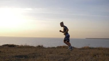 Genç sporcu gökyüzüne karşı denizden taklalar atıyor.