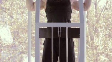 Sağlıklı yaşam tarzı, güzel spor vücudu olan çekici sporcu spor salonundaki güç egzersizi sırasında simülatöre yanaşıyor.