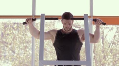 Spor yaşam tarzı, güzel atletik vücudu olan kaslı sporcu spor salonunda egzersiz yaparken simülatöre yanaşıyor.
