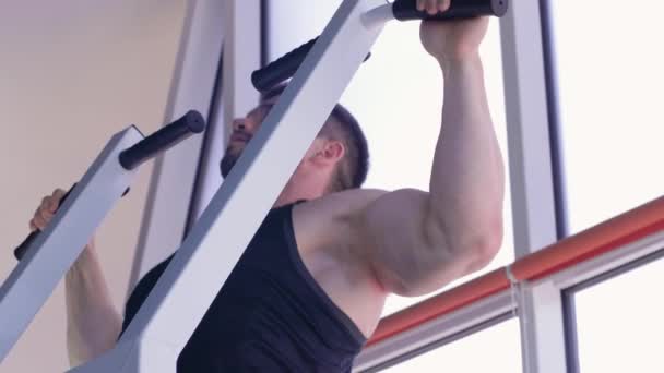 Sport edzés, erős testépítő srác gyönyörű atlétikai test húzza fel a szimulátor alatt teljesítmény edzés tornaterem — Stock videók