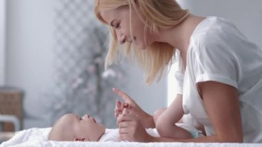 Neşeli anne, yeni doğmuş sevimli bebeğine dokunur ve öper.