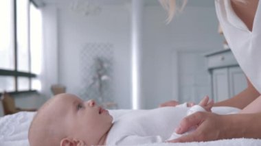 Annelik, gülümseyen anne konuşuyor ve masasını değiştiren küçük kızıyla nazik bir oyun oynuyor.