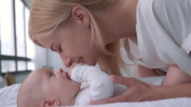 Annelik, sarışın anne konuşuyor ve küçük kızıyla oynuyor. O da masa değişiminde yatıyor.