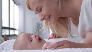 Ebeveyn, gülümseyen anne masasını değiştiren küçük kızıyla nazikçe oynuyor.