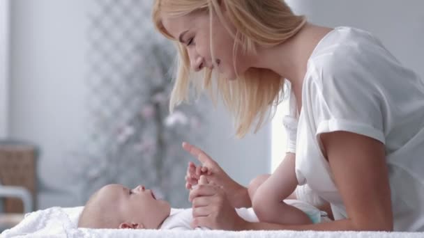 Fröhliche Mutter berührt und küsst ihr entzückendes neugeborenes Mädchen, das aus nächster Nähe auf dem Wickeltisch liegt — Stockvideo