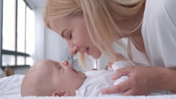 Mãe amor, jovem pai gentilmente toca e beija seu bebê adorável menina que se deita na mesa de mudança — Vídeo de Stock