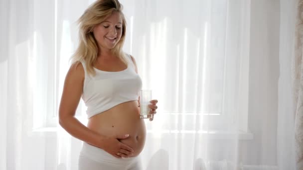 Näring av mjölkprodukter under graviditeten, framtida mamma håller glasmjölk och ler — Stockvideo