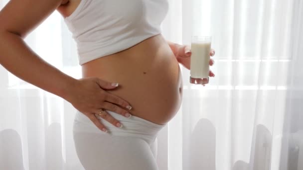 Pregnant girl holds glass milk on background of big tummy, milk products — Stock Video