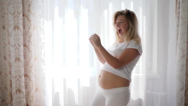 Ευτυχισμένη έγκυος γυναίκα με γυμνή κοιλιά θαυμάζει υπερηχογράφημα εικόνα βρέφος — Αρχείο Βίντεο