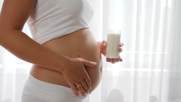 Mujer embarazada disfruta de la leche con un vientre grande en el interior, la nutrición de los productos lácteos — Vídeo de stock