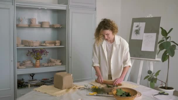 Гончарна майстерність, керамістська майстриня кидає глину з прокатним штифтом на стіл для виготовлення керамічного посуду — стокове відео