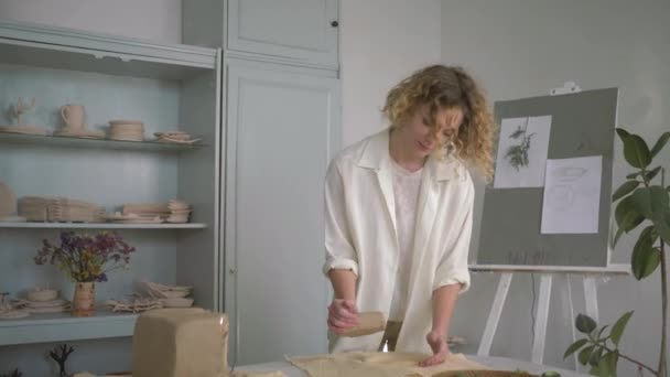 Талановита професійна керамічна жінка робить глину м'якшою і плоскою на столі для виготовлення глиняного посуду — стокове відео