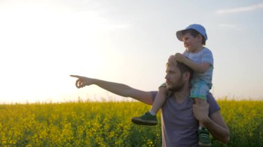 Güneşli havada baba ve oğulun tarla yürüyüşü, küçük çocukla birlikte adamlar tarladan tarlaya, ufuktan ufka geziyorlar.,