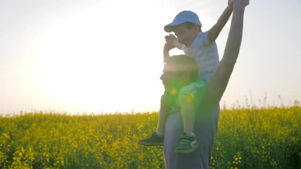 Porträtt av lycklig familj på fältet, far med son på halsen leker i blom, pappa och barn luras — Stockvideo