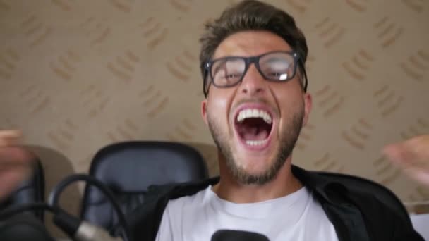 Šílený muž v brýlích se širokými otevřenými ústy křičí do mikrofonu v nahrávacím studiu — Stock video