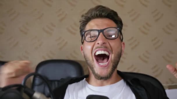 넓은 입을 벌리고 있는 안경을 쓴 미친 남자 가 실내의 마이크에 소리를 지르고 있다 — 비디오