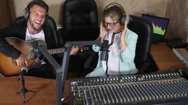 ラジオのインタビューで幸せな女性の近くに座ってギターを弾く男 — ストック動画