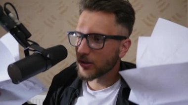 Spor müsabakası yorumcusu bağırıyor ve gazeteleri mikrofonun yanına fırlatıyor