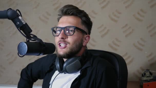 Портрет милого радіоведучого в окуляри говорить в мікрофоні — стокове відео