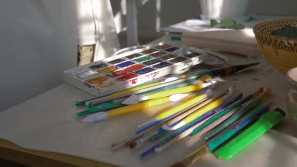Profissão de artista, as mãos de pintor de mulher escolhem a escova perto da paleta de pinturas para desenhar no closeup de sala de trabalho — Vídeo de Stock