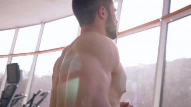 Spor yaşam tarzı, spor merkezinde koşu bandında koşan kaslı çıplak vücut geliştirici.