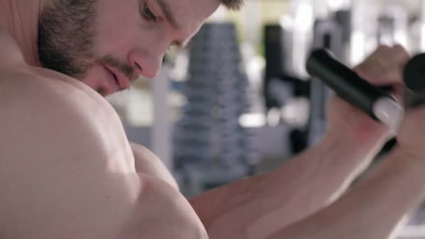 Здоровый образ жизни, мышечные виды спорта мужчины делают силовые упражнения на мышцах рук на тренажере во время силовых тренировок в фитнес-клубе — стоковое видео
