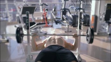 Güç antrenmanı, güçlü kaslı vücut geliştirici halterle ağırlık kaldırırken spor salonunda egzersiz yapıyor.