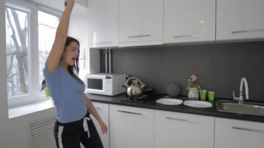 Mutlu, komik ev hanımı kadın evde yemek masasında bulaşıklarla şarkı söylüyor.