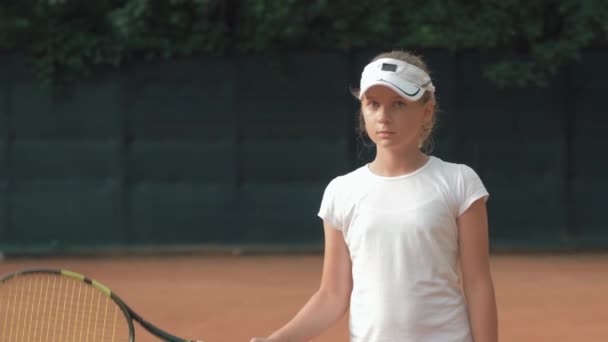 Competitieve geest, portret van tennisspeelster meisje met racket in handen op rode baan op open lucht — Stockvideo