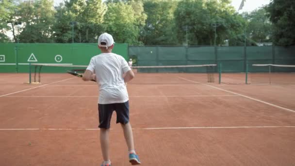Tenis profesional, jóvenes jugadores de tenis niño y niña juegan deportes con la ayuda de la pelota y raquetas en la cancha roja — Vídeos de Stock