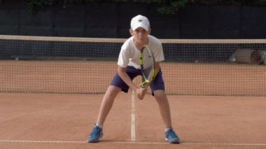 Tenis antrenmanı, kasıtlı genç çocuk sahada top olmadan servis tekniği uyguluyor ve maça hazır.
