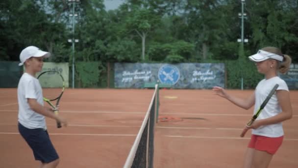 Začátek tenisového zápasu, dívka a chlapec tenisté setkání po síti a pozdravy navzájem třesoucí se ruce před turnajem na hřišti a chůze na pozicích — Stock video