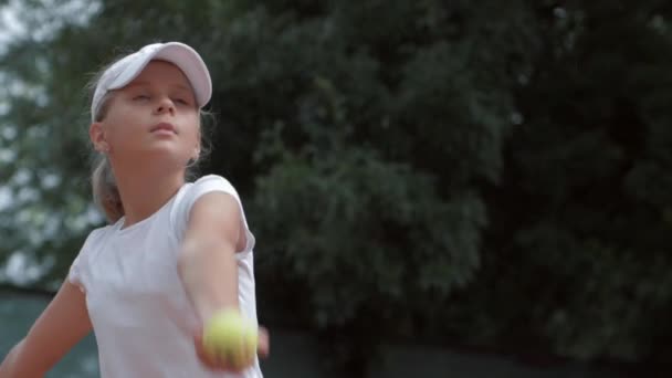 Determined ambitious tennis player teen girl hitting racket on ball at court close up — ストック動画