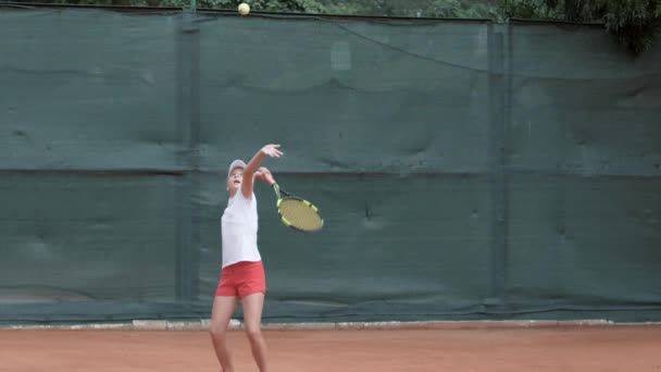 Professional sport, tennis player adolescent girl concentrating and focusing on game then hitting racket on ball at professional court — Stock Video