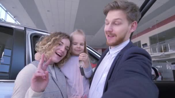 Verbraucherfamilie mit niedlicher kleiner Tochter mit Schlüsseln fotografiert Handy am Telefon in der Nähe eines neu gekauften Automaten im Autohaus — Stockvideo