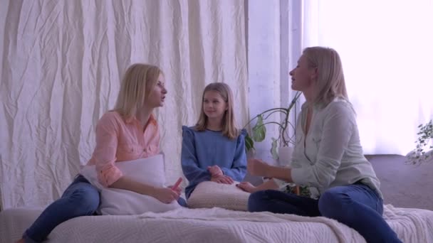 Rodinný volný čas, matka a dcery klábosení a bavit se spolu v posteli doma — Stock video