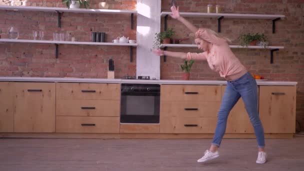 Счастливая спортивная девушка делает гимнастический флип в замедленной съемке на кухне дома — стоковое видео
