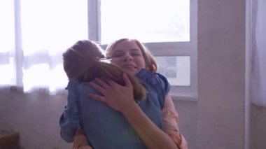 kız kardeş ilişkisi, sarışın kızlar birbirlerine sarılırlar ve evlerinin penceresinin yanında şefkatle bakarlar.