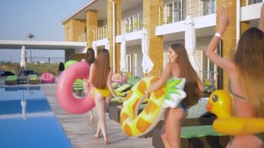 Yaz eğlencesi, mutlu kadın arkadaşlar şişme yüzüklü mayo giyerler tatil boyunca havuz kenarında dinlenirler.
