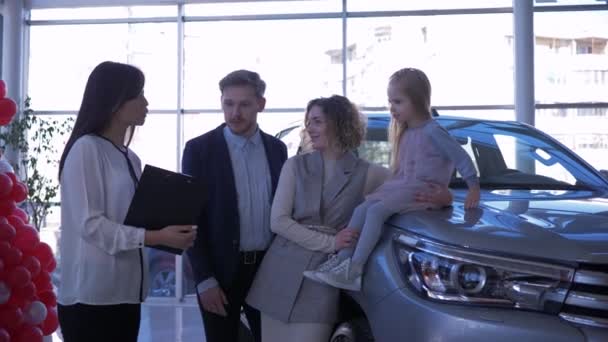 Auto dealership, young buyers family with kid girl communicate with car manager about purchase new automobile at Auto sale center — Stock Video