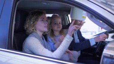 Aile ulaşımı, çocuk sahibi genç müşteri ailesi, araba galerisinden araç alırken iç mekanda oturmayı dikkatlice düşünün.