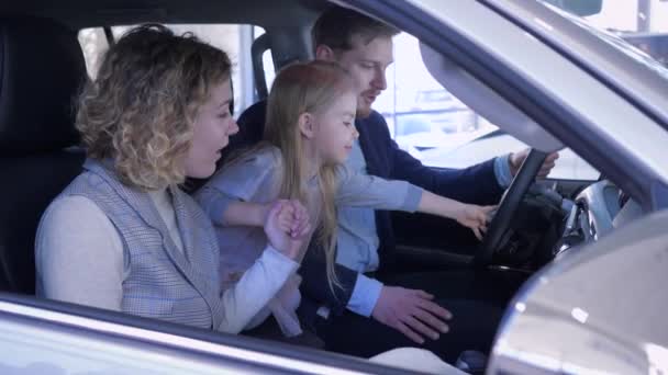 Araba galerisindeki aile, çocuk sahibi mutlu karı-koca araba fuarında kabinde otururken yeni bir araba almayı düşünüyorlar.
