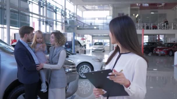 Porträt des Autoverkäufers asiatische Frau im Hintergrund glückliche Kunden Familie mit Kind Mädchen der Besitzer gekauft Fahrzeug im Auto-Verkaufszentrum — Stockvideo