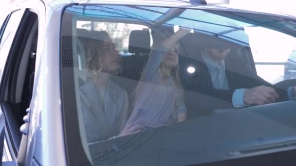 Portret szczęśliwej rodziny w salonie samochodowym, młodzi rodzice z dziewczynką uśmiechającą się i przytulającą podczas siedzenia w salonie samochodowym w centrum samochodowym — Wideo stockowe