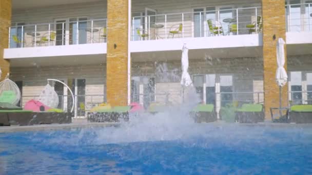 Glücklich schlanke sexy Mädchen mit langen Haaren in Badeanzügen springen Händchen haltend im blauen Pool bei einer Poolparty während der Sommerferien auf einer Strandparty — Stockvideo